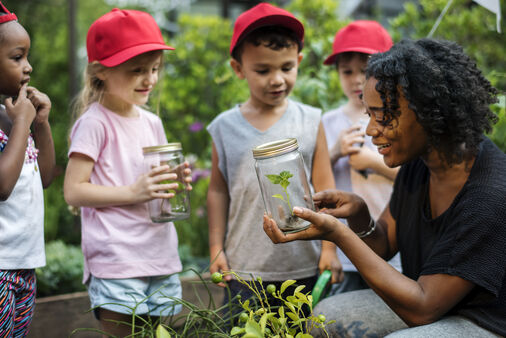 Teacher showing a plant to a group of young students