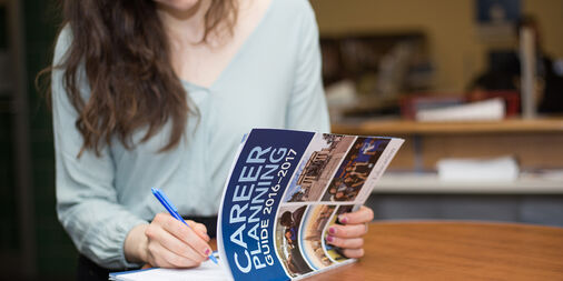 woman writing in journal titled "career planning"